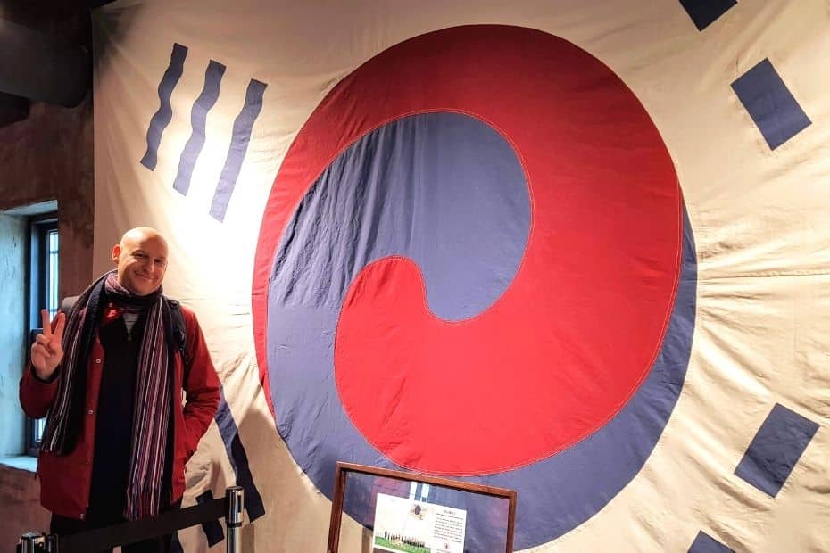 Joel, an expat in Korea, standing by an old Korean flag